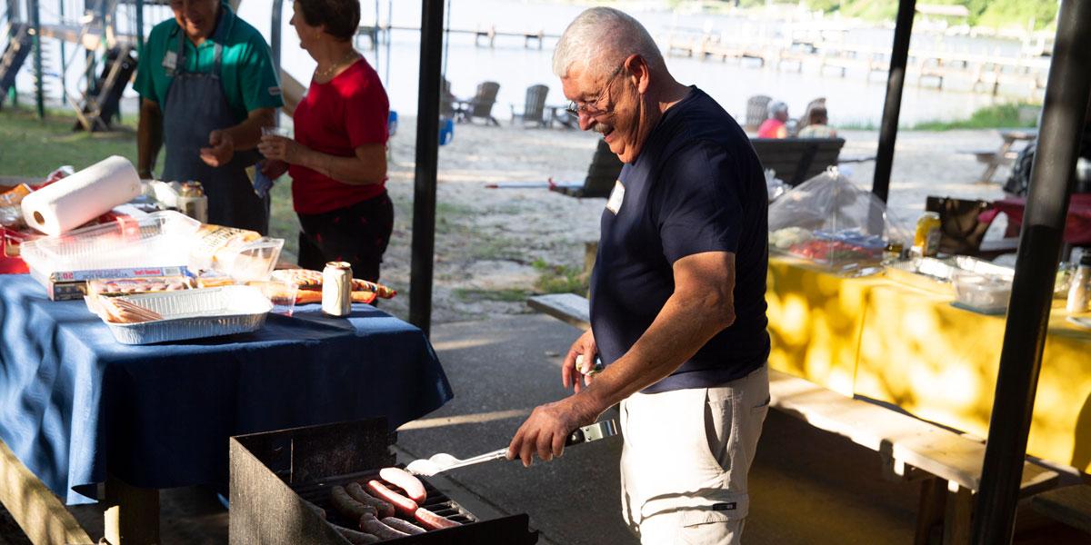 Man outside cooking food on a grill.