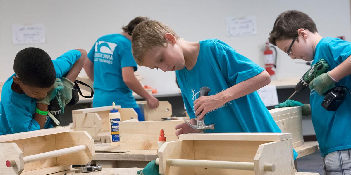 Kids in college building with woodworking tools.